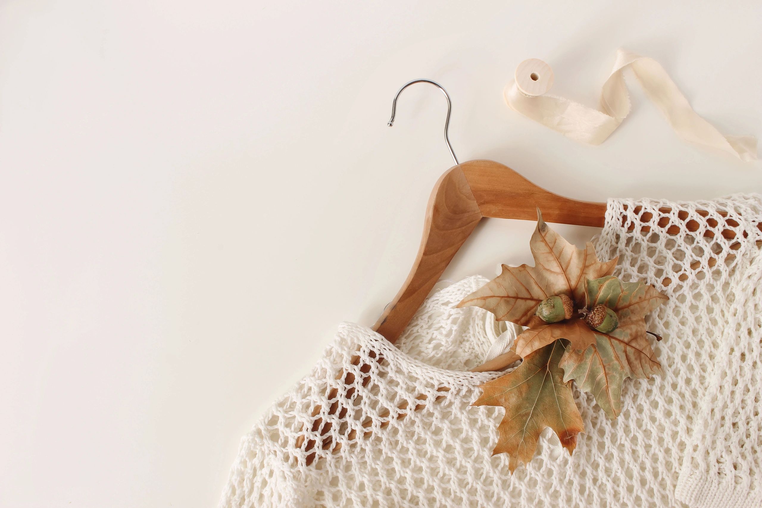 Minimal flat lay of a neutral knit sweater on a hanger