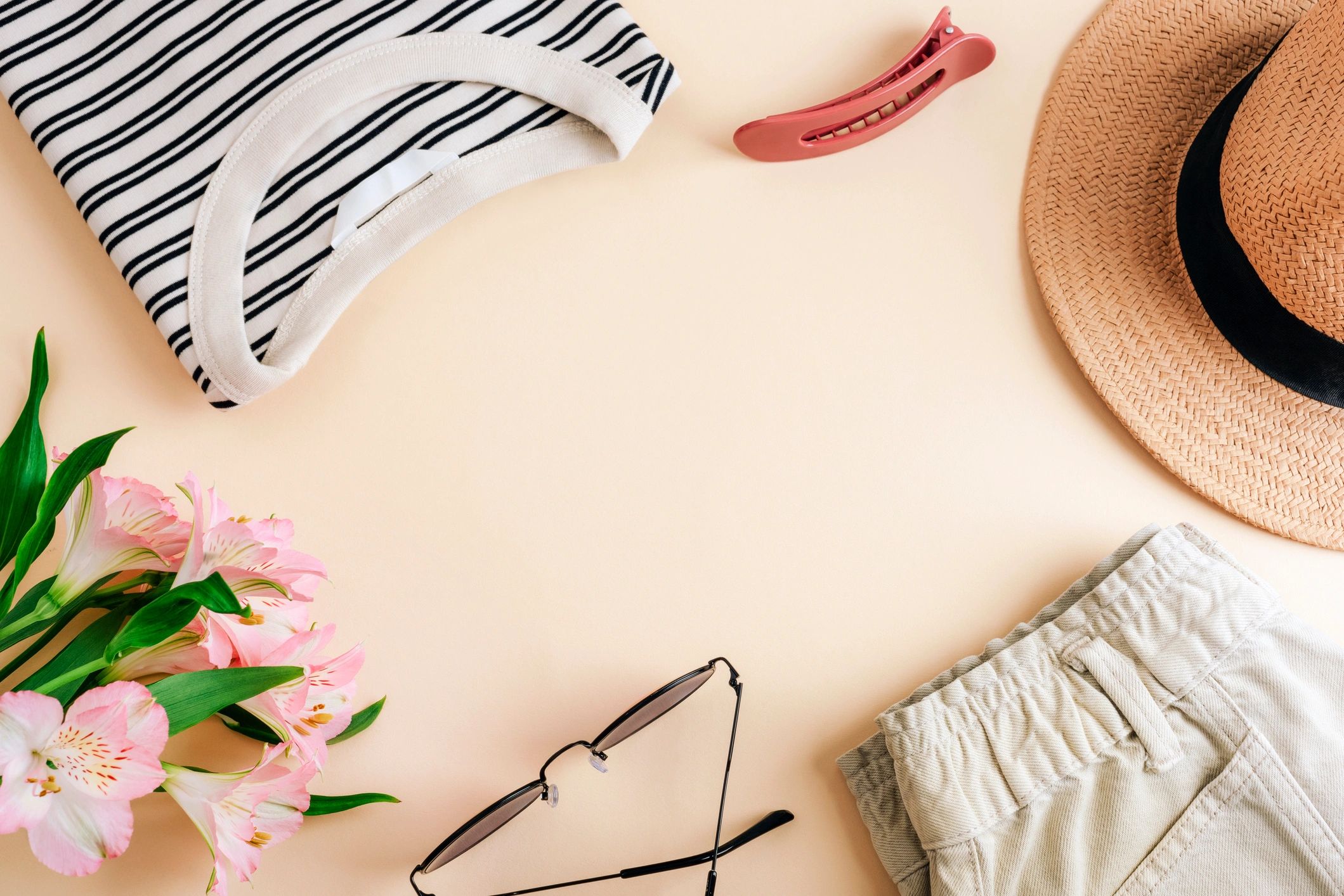 Neutral clothing flat lay with accessories on beige background